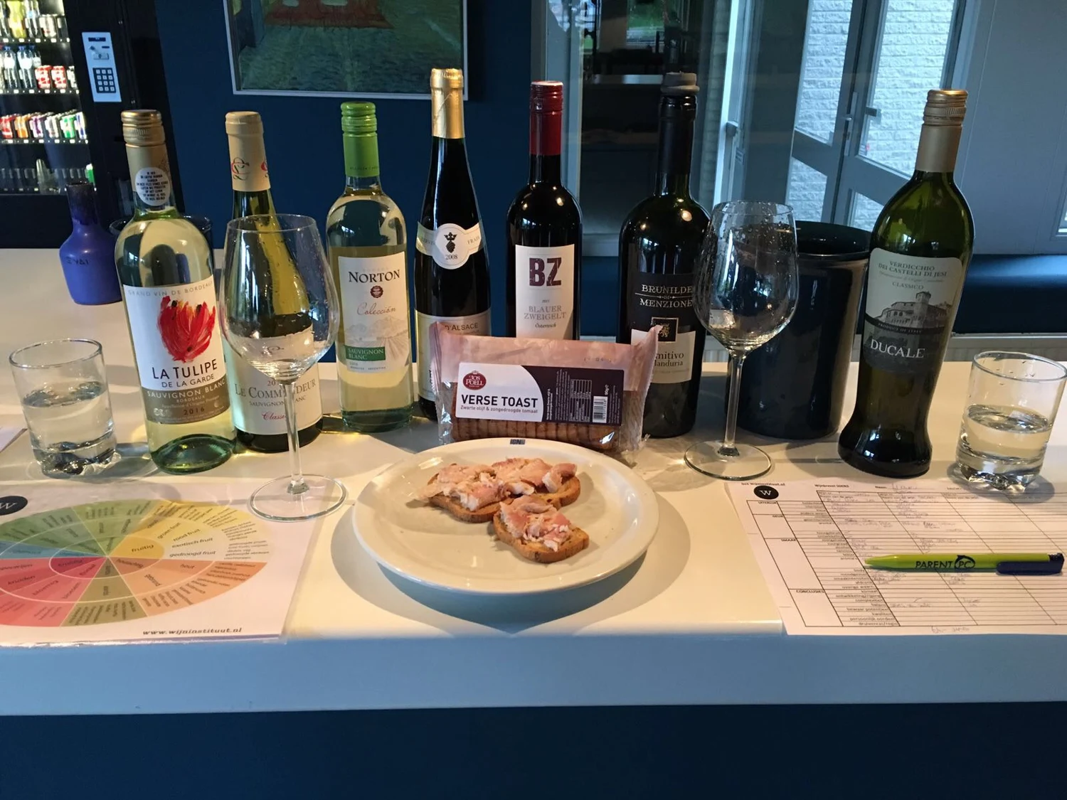 Wijnflessen, proefglazen en notities op tafel tijdens de SDEN3-proefavonden in 2018.